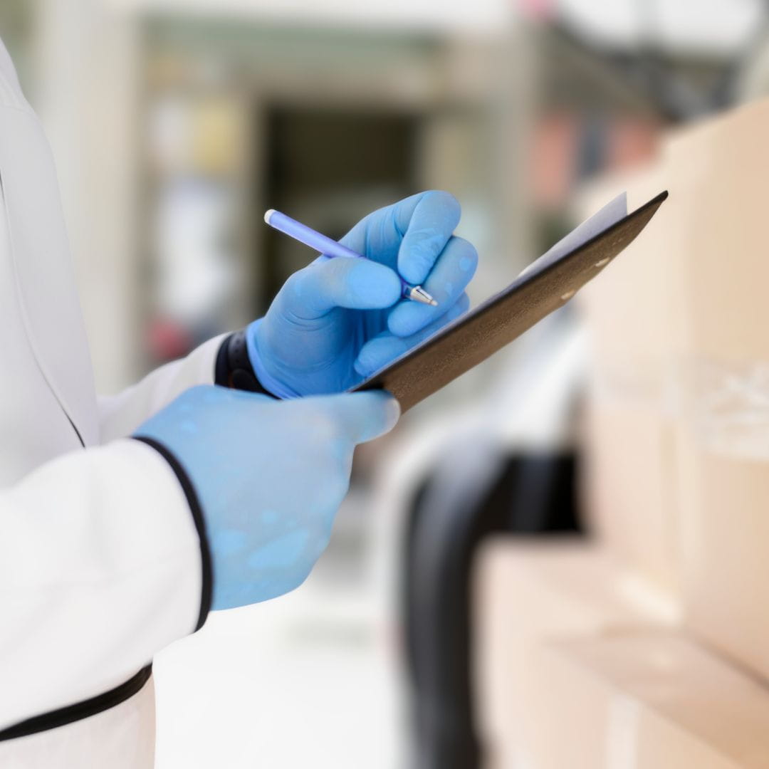 Quality inspector in protective gear checking a temperature-sensitive pharmaceutical shipment for charter air transport.